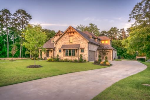 a house with a driveway and a tree in the middle of a grassy area