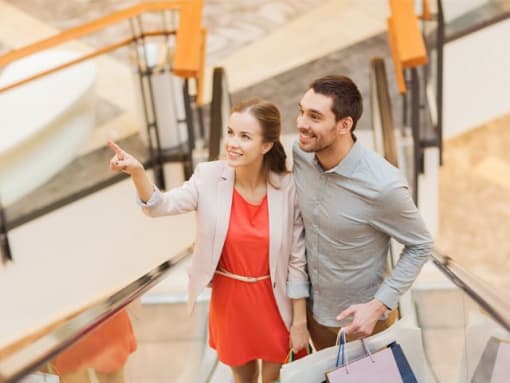 a man and woman walking down an escalator with shopping bags
