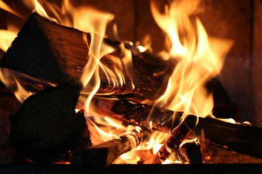 A close up of a fire with flames and burning wood.