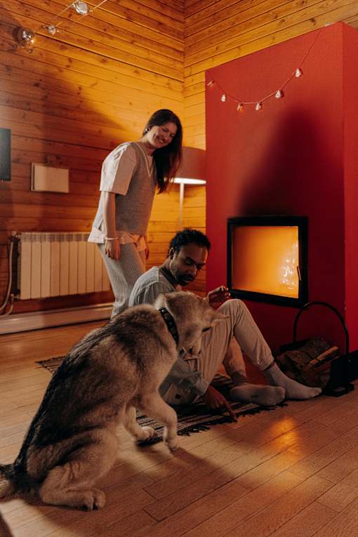 A woman and a man are standing in a room with a dog.