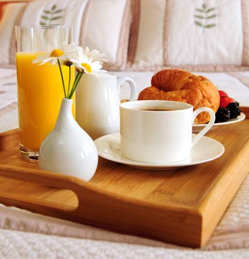 A breakfast tray with coffee, croissants, and orange juice.