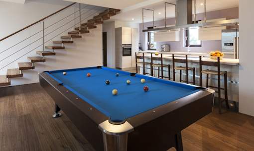 A pool table in a room with a staircase.