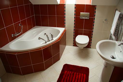 A red bathroom with a white tub and toilet.