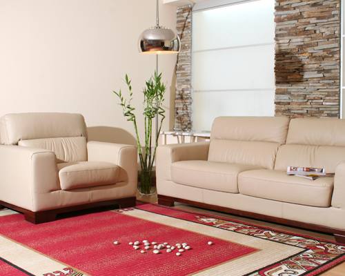 A living room with a sofa, armchair, and a rug with scattered pills.