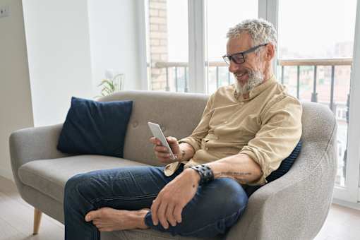 a man sitting on a couch looking at his cell phone