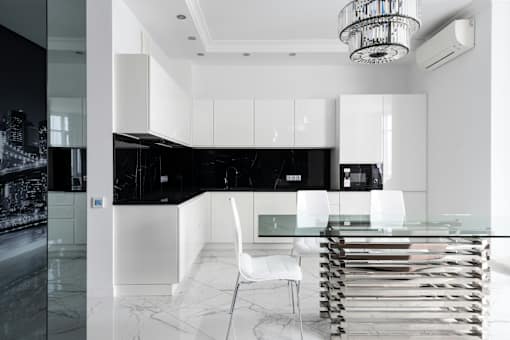 A modern kitchen with black and white cabinetry and a glass table.