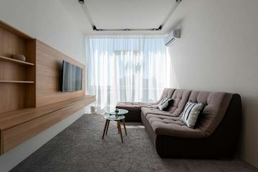 A modern living room with a brown sofa and a wooden entertainment unit.
