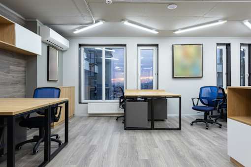 A modern office space with a wooden desk and blue chairs.