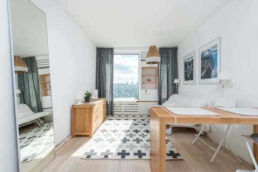 A well-lit, modern bedroom with a large window and a view of the city.