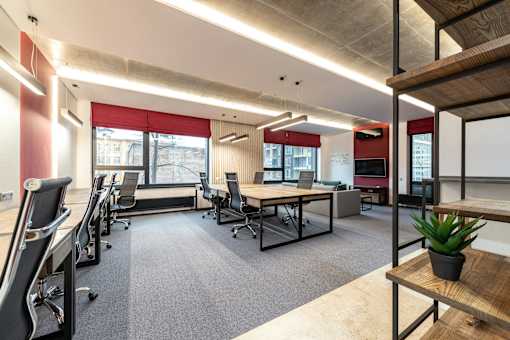 A modern office space with desks, chairs, and a plant.