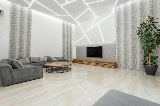 A living room with a grey sofa, a wooden coffee table, a flat screen TV, and a potted plant.