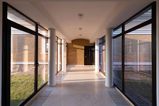 A long hallway with a brick wall and white columns.
