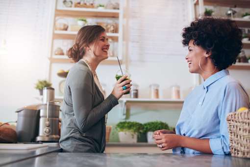 two women sitting in a kitchen having a conversation