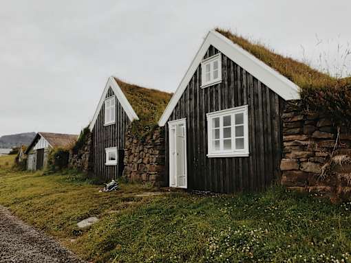 A small house with a grass roof sits in a field.