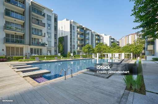 A modern apartment complex with a pool in the foreground.