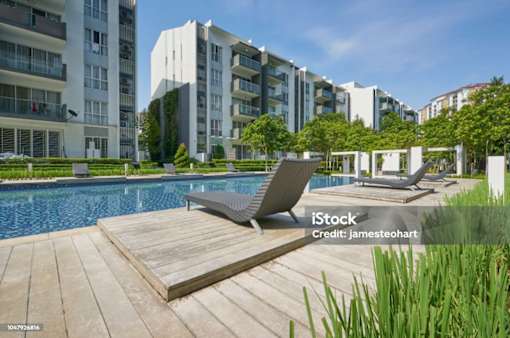A poolside deck with a lounge chair and a building in the background.