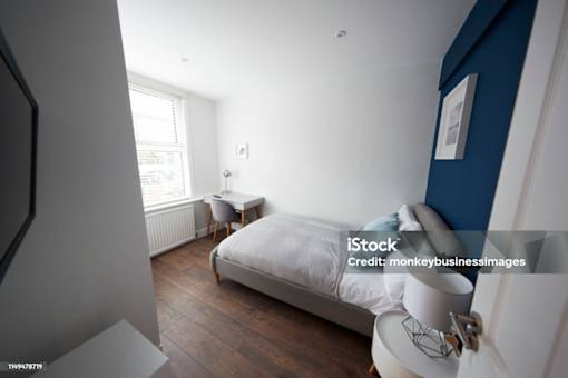 A bedroom with a bed, chair, and window.