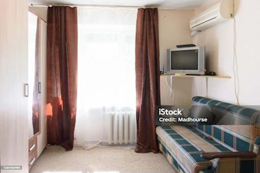 A living room with a sofa, television, and curtains.