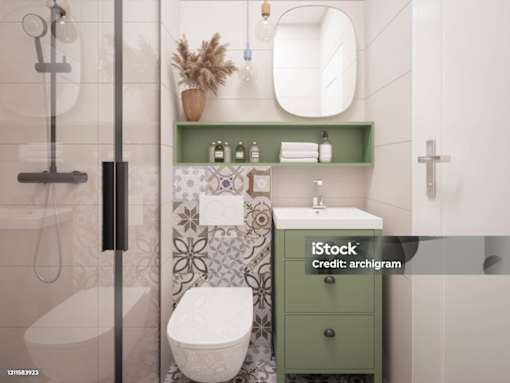A white toilet with a green cabinet and a mirror above it.
