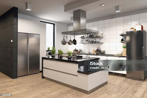A modern kitchen with a black refrigerator and wooden flooring.