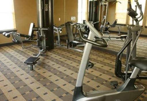 A gym with a variety of exercise equipment including treadmills, stationary bikes, and weight machines.