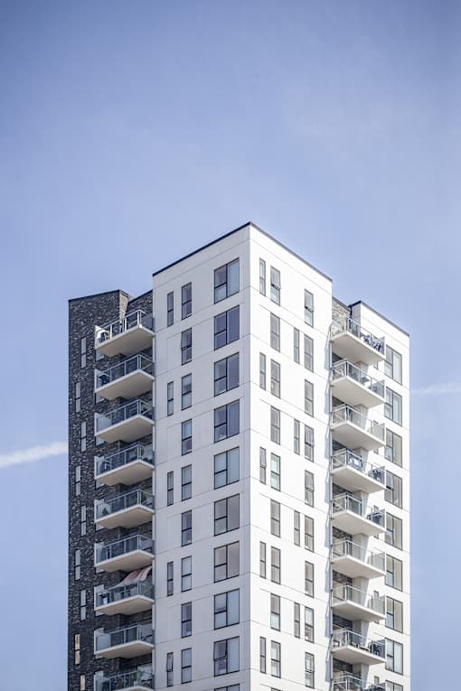 A tall white building with balconies on each floor.