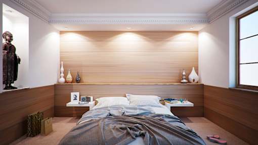 A modern bedroom with a large bed and a statue on the left side.
