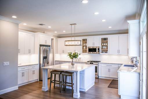 A modern kitchen with a central island, bar stools, and a refrigerator on the side.