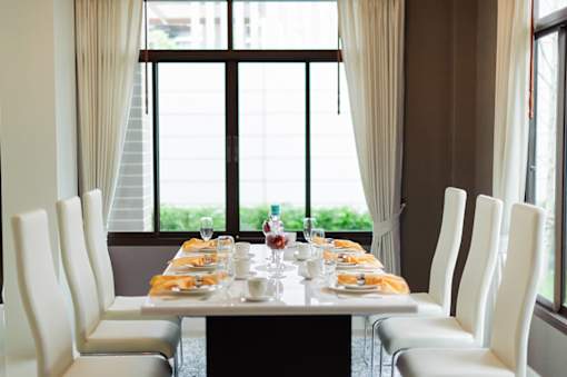 a dining table with white chairs in front of a window