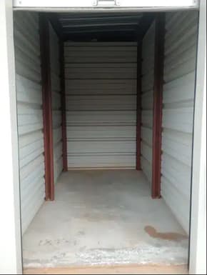 the inside of an empty outhouse with white walls and a door
