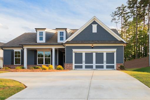 A house with a grey garage door and a brown roof.