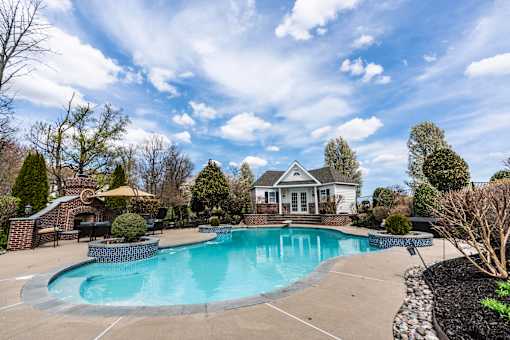 A large swimming pool in a backyard with a house in the background.