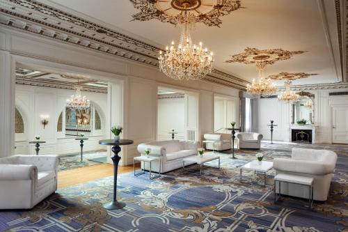 A luxurious living room with a chandelier, sofas, and a patterned rug.