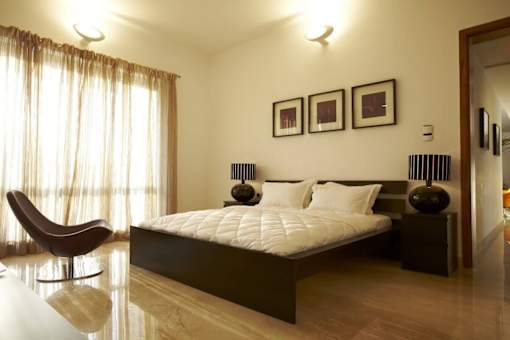 A bedroom with a large bed and a chair.