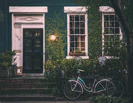 A bicycle is parked in front of a house with a door numbered 106.