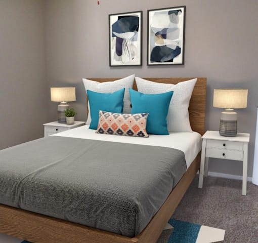 A bed with a grey cover and two pillows with different patterns.