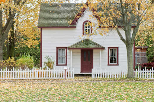 A white house with a red door and a green roof.