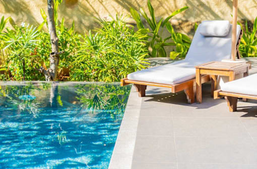 A poolside lounge chair with a white cushion and wooden frame at Bluebell Ridge, Denver CO 80202