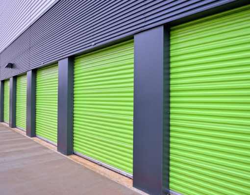 A series of green storage units with grey pillars and a grey roof.