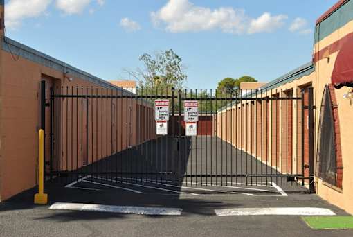 A black gate with a yellow post and a sign on it.