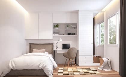 A bedroom with a bed, desk, and chair.
