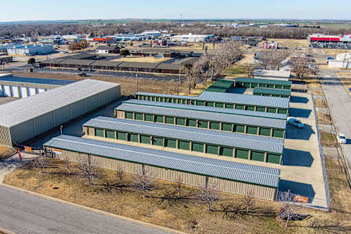 A large industrial building with a green roof is surrounded by a parking lot.