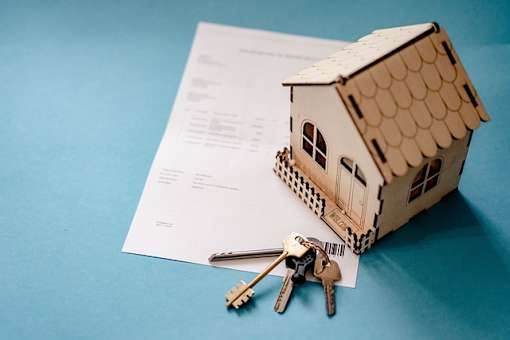 A small house model with a set of keys on top of a document.