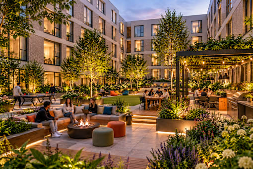 A group of people are sitting around a fire pit in a courtyard.