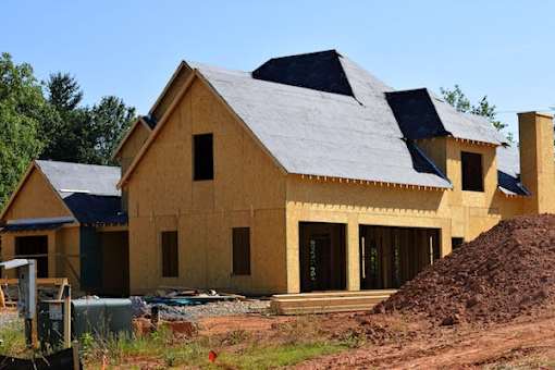 A house under construction with a grey roof and wooden walls.