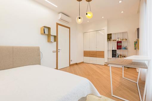 A bedroom with a bed, desk, and shelves.