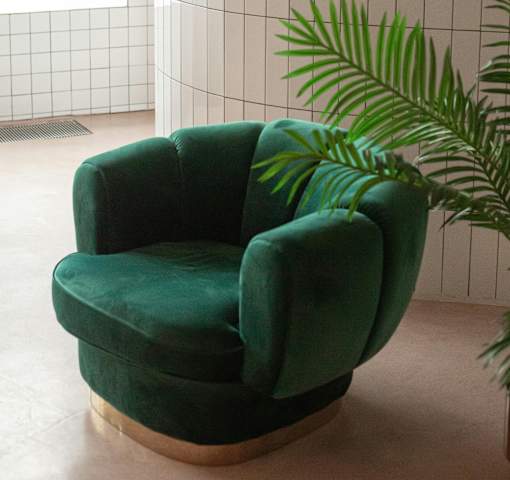 A green armchair with a wooden base is placed in a room.