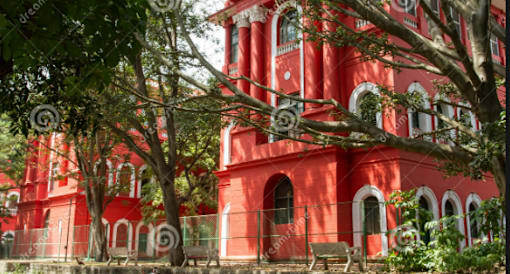 A red building with arched windows and a fence in front.