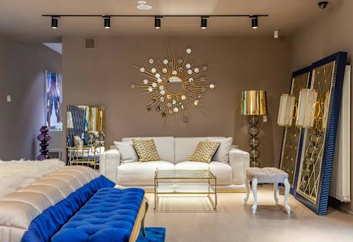 A living room with a white couch and a blue tufted bench.
