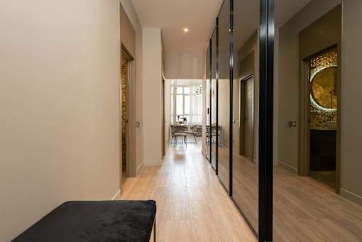 A long hallway with a black bench on the left side.